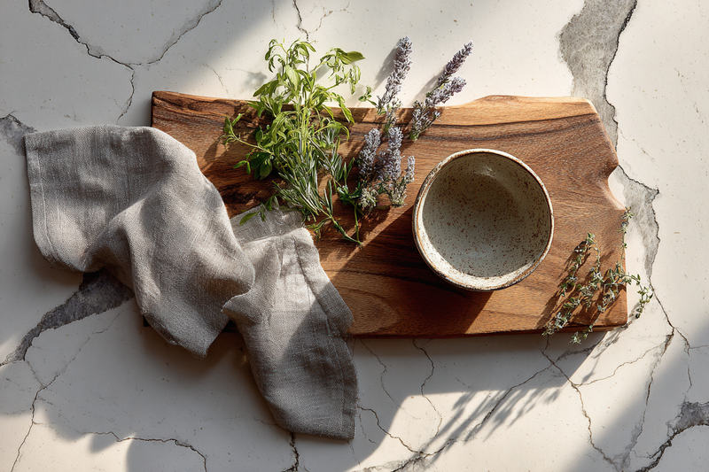Styled quartz countertop vignette with a board, herbs and linen